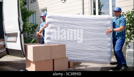 Matelas de transport efficace pour déménageurs pendant la livraison le jour de déménagement. Travailleurs heureux déchargent. Professions possibles : déménageurs Banque D'Images