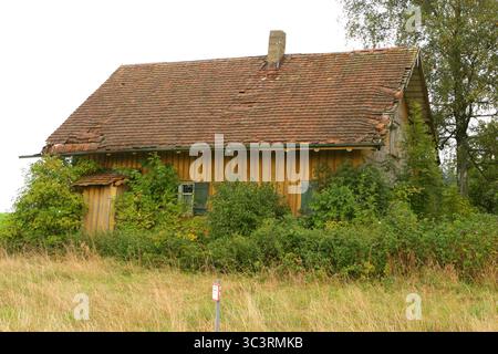 Petite maison ancienne avec un toit vert et une cheminée Banque D'Images