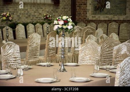Table à manger dans un restaurant avec un bouquet de fleurs. Salle de banquet de mariage Banque D'Images