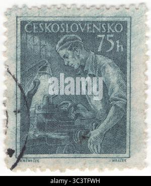 TCHÉCOSLOVAQUIE - 1954 septembre 25 : timbre-poste bleu foncé à 75 haléř représentant l'opérateur de Lathe. Un tour est une machine-outil qui fait tourner une pièce autour d'un axe de rotation pour effectuer diverses opérations telles que la coupe, le ponçage, le moletage, le perçage, la déformation, surfaçage, filetage et tournage, avec des outils appliqués à la pièce pour créer un objet symétrique autour de cet axe. Les tours sont utilisés dans le tournage du bois et le travail des métaux. Les tours de travail des métaux les plus convenablement équipés peuvent être utilisés pour produire la plupart des solides de révolution, des surfaces planes et des filetages ou des hélices Banque D'Images