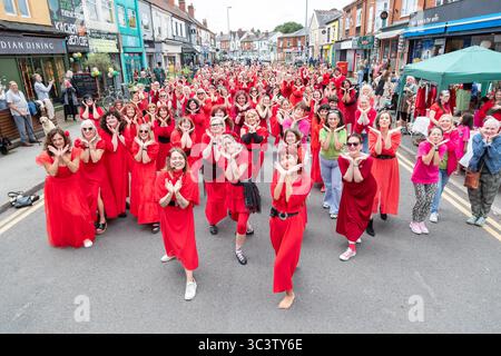 Birmingham, Royaume-Uni. 27 juillet 2025. Trois cents personnes se réunissent pour exécuter une routine de danse appelée Most Wuthering Heights Ever à Kings Heath, Birmingham, Royaume-Uni. Les participants, tous vêtus de rouge, ont été adressés par Jess Phillips, députée travailliste de Yardley, Birmingham, avant de recréer le clip de la chanson emblématique de Kate Bush, « Wuthering Heights ». L'événement amasse des fonds pour les éducatrices d'autonomisation des femmes et de rétablissement et les associations caritatives ANAWIM. Crédit : Peter Lopeman/Alamy Live News Banque D'Images