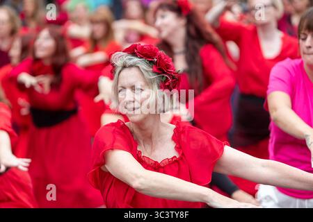 Birmingham, Royaume-Uni. 27 juillet 2025. Trois cents personnes se réunissent pour exécuter une routine de danse appelée Most Wuthering Heights Ever à Kings Heath, Birmingham, Royaume-Uni. Les participants, tous vêtus de rouge, ont été adressés par Jess Phillips, députée travailliste de Yardley, Birmingham, avant de recréer le clip de la chanson emblématique de Kate Bush, « Wuthering Heights ». L'événement amasse des fonds pour les éducatrices d'autonomisation des femmes et de rétablissement et les associations caritatives ANAWIM. Crédit : Peter Lopeman/Alamy Live News Banque D'Images