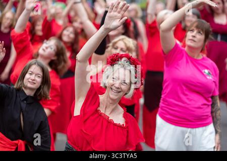 Birmingham, Royaume-Uni. 27 juillet 2025. Trois cents personnes se réunissent pour exécuter une routine de danse appelée Most Wuthering Heights Ever à Kings Heath, Birmingham, Royaume-Uni. Les participants, tous vêtus de rouge, ont été adressés par Jess Phillips, députée travailliste de Yardley, Birmingham, avant de recréer le clip de la chanson emblématique de Kate Bush, « Wuthering Heights ». L'événement amasse des fonds pour les éducatrices d'autonomisation des femmes et de rétablissement et les associations caritatives ANAWIM. Crédit : Peter Lopeman/Alamy Live News Banque D'Images