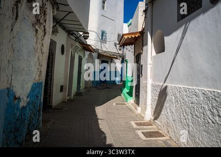 Photo d'une ruelle colorée avec des rayures vertes et bleues peintes sur un mur étroit à Tanger, Maroc. Banque D'Images