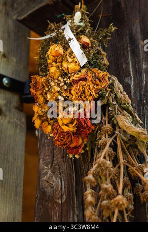 Herbes séchées et fleurs suspendues sur le poteau en bois de vieux bâtiment traditionnel Banque D'Images