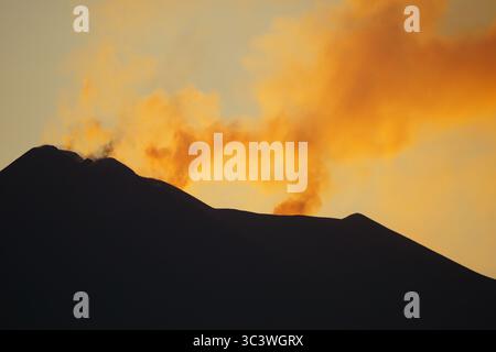 Coucher de soleil du soir vue orange sur l'Etna, Italie, suite à l'éruption volcanique de juin 2025 avec fumée, vapeur du sommet, sommet Banque D'Images