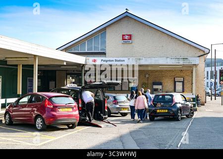 Paignton, Devon, Angleterre, Royaume-Uni - 24 avril 2025 : voitures et passagers devant l'entrée de la gare de Paignton Banque D'Images