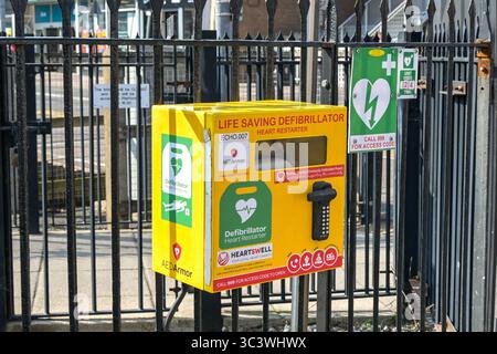 Paignton, Devon, Angleterre, Royaume-Uni - 24 avril 2025 : boîte contenant un défibrillateur de redémarrage cardiaque pour une utilisation en cas d'urgence médicale attaché à des rampes Banque D'Images