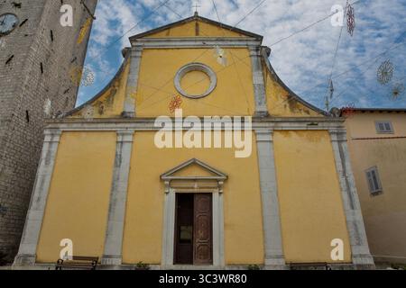 Vue de face de l'église baroque jaune de préparation Stephen avec colonnes de pierre et fronton triangulaire décoré de guirlandes de fleurs colorées sur ciel bleu Banque D'Images
