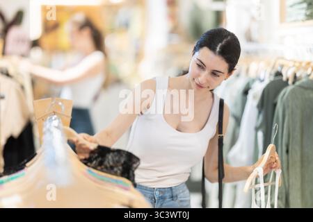 La cliente choisit un chemisier singulet dans le magasin de marque Banque D'Images