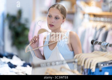 La cliente choisit un chemisier singulet dans le magasin de marque Banque D'Images