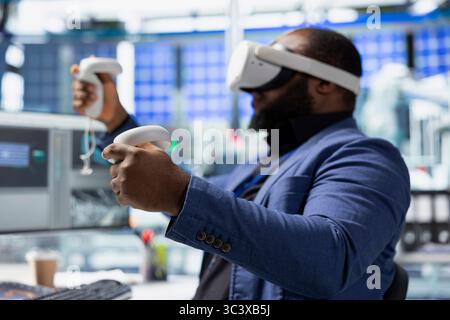 Technicien afro-américain dans l'usine de panneaux solaires utilisant des lunettes VR, optimisant les mises en page à l'aide d'un logiciel de CAO. Ouvrier d'usine photovoltaïque utilisant la technologie de réalité virtuelle pour faire des arrangements. Banque D'Images