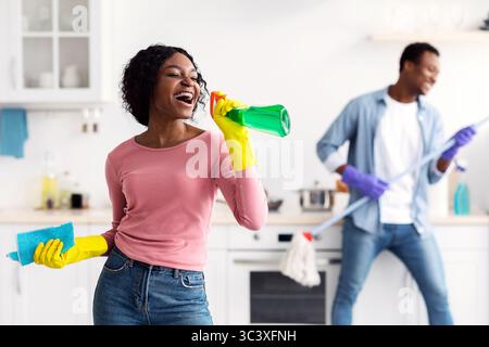 Femme noire s'amusant avec son petit ami tout en nettoyant la cuisine Banque D'Images
