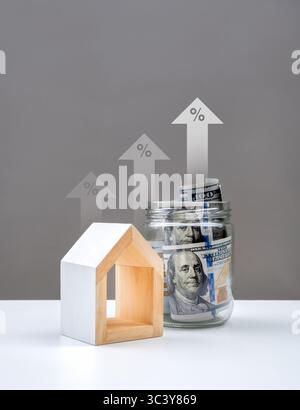 Impôt foncier, impôt foncier et immobilier, taux d'intérêt hypothécaire et de refinancement, concept immobilier et financier. Billets de 100 dollars en pot de verre et maison blanche Banque D'Images
