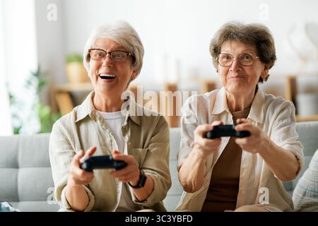 Deux amies seniors ou sœurs jouant au jeu vidéo console à la maison. Banque D'Images