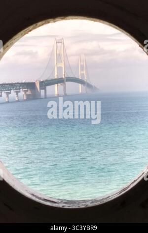 Une vue brumeuse du pont Mackinac à travers le hublot du phare Old Mackinac point. Phare historique restauré de 1889 dans le Michigan. Banque D'Images
