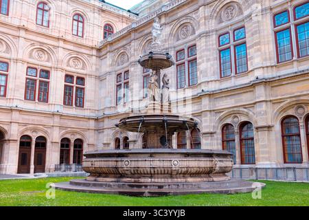 Fontaine dans la cour de l'Opéra national de Vienne, entourée d'une architecture Renaissance ornée et de fenêtres historiques un après-midi d'été. Banque D'Images