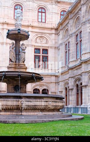 Fontaine dans la cour de l'Opéra national de Vienne, entourée d'une architecture Renaissance ornée et de fenêtres historiques un après-midi d'été. Banque D'Images