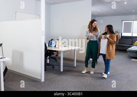 Diverses collègues féminines marchant ensemble à travers des tasses de bureau ouvertes, espace de copie Banque D'Images