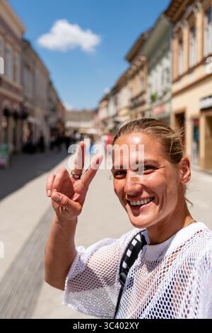 Heureux voyageur urbain prenant selfie et faisant V signe à l'extérieur Banque D'Images