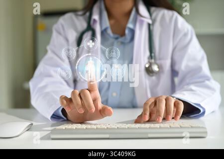 Médecin utilisant une interface médicale virtuelle avec des icônes numériques pour la technologie de soins de santé et les données des patients Banque D'Images