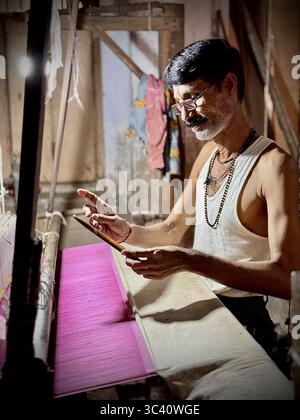 Un homme tisse des tissus de soie pour saris sur un métier à tisser antique. Le sari se compose d'un tissu sans couture d'environ 1,20 mètres de large et d'environ 6 mètres de long. Trad Banque D'Images
