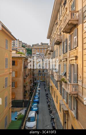 La lumière du soleil illumine une charmante rue étroite de Gênes, en Italie, avec des bâtiments historiques et un véhicule garé Banque D'Images