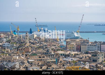 Les ferries accostent dans le port de Gênes derrière une ligne d'horizon dense de toits en ardoise, de dômes historiques et de grues le long de la côte ligure Banque D'Images