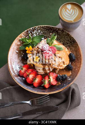 Pile de délicieuses crêpes garnies de crème fouettée et de baies fraîches, joliment décorées de fruits. Savoureux petit déjeuner maison ou brunch servi Banque D'Images