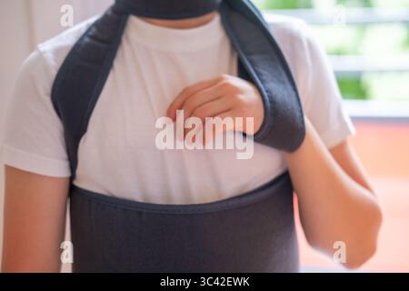 Jeune personne portant une bandoulière orthopédique thérapeutique pour soutenir le membre blessé, bandage d'épaule, soutien post-chirurgical, soins médicaux, soins de santé, Banque D'Images