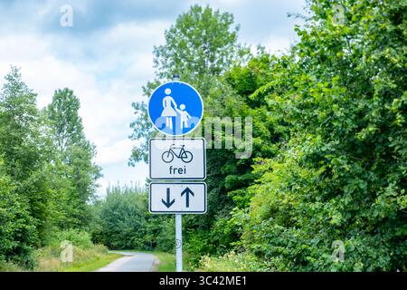 Panneau de zone piétonne avec symbole vélo autorisé sur le chemin rural allemand, panneau bleu piéton et enfant, chemin à usage mixte, entouré d'arbres verts, deux- Banque D'Images