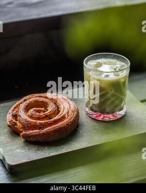 Latte matcha glacé rafraîchissant aux fraises servi avec des pâtisseries variées sur une table en bois rustique dans un café confortable. Ambiance de café esthétique, perfe Banque D'Images