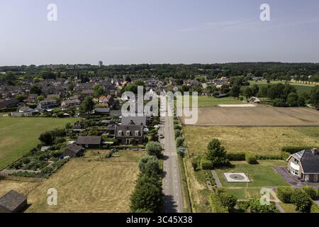 Vue aérienne d'une route traverse le cœur du village pittoresque, bordé de maisons soignées et de champs dorés, Werkhoven, Utrecht, pays-Bas. Banque D'Images