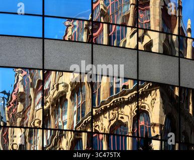 Reflets surréalistes d'un bâtiment édouardien orné dans les fenêtres d'un immeuble de bureaux moderne - d'un design très différent - sur Chepstow St, Manchester. Banque D'Images