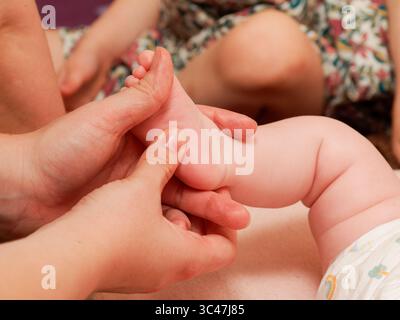 Massage des pieds pour bébés dans le cadre d'une séance de thalassothérapie au spa, gros plan sur le soin de bien-être des nourrissons. Banque D'Images