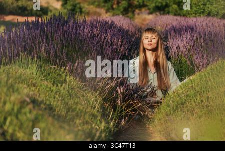 Femme appréciant le sentiment de calme dans le champ de Lavender Banque D'Images
