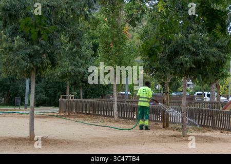 Viladecans.Barcelona - 28 juillet 2025 : une scène de soins de la nature urbaine, avec une personne irriguant diligemment le feuillage pour maintenir un environnement vibrant et sain Banque D'Images