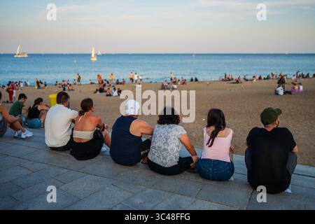 Groupe de personnes profitant de la plage de Barceloneta au coucher du soleil, Barcelone, Espagne Banque D'Images