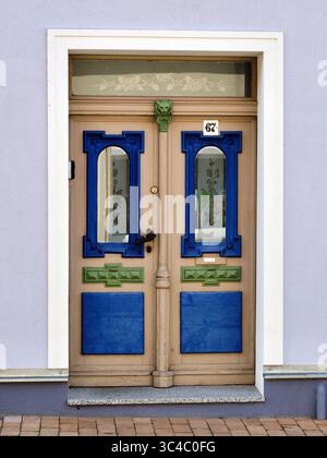 Porte décorative beige avec des panneaux peints bleus et verts frappants et des détails en verre floral, photographiée à Vorpommern, Allemagne. Partie de la série « c Banque D'Images