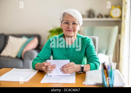 Femme âgée assise dans le salon et faisant de la paperasse Banque D'Images