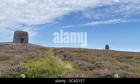 Deux grands cairns en pierre au sommet de la colline Twin Law, marquant des tombes légendaires, se dressant sur la lande de bruyères sous un ciel immense avec des vues panoramiques à travers les frontières Banque D'Images