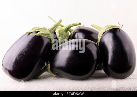 Un tas d'aubergines noires sont empilées les unes sur les autres. Les aubergines sont toutes de tailles et de formes différentes, mais elles ont toutes une couleur et un tex similaires Banque D'Images