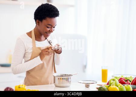 Dame prenant photo du dîner dans une casserole cuisson dans la cuisine Banque D'Images