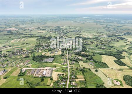 village avec bâtiments de ferme parmi les champs verdoyants en campagne. vue aérienne depuis un drone volant. Banque D'Images