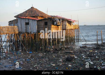 Restaurant Obama sur pilotis au-dessus de l'eau, mais beaucoup de déchets sales autour à marée basse. Soirée. Conakry, Guinée. Banque D'Images