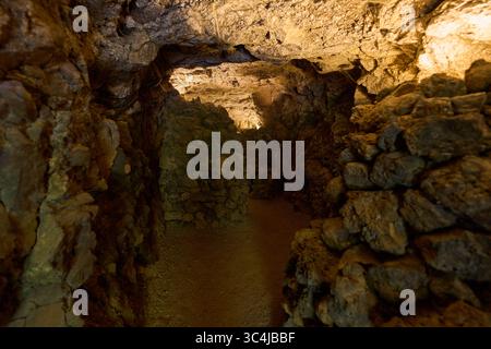 Intérieur d'une grotte volcanique formée par un ancien tube de lave avec des murs en pierre brute et un éclairage tamisé Banque D'Images