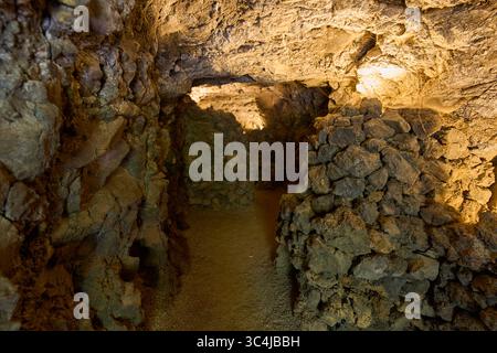 Intérieur d'une grotte volcanique formée par un ancien tube de lave avec des murs en pierre brute et un éclairage tamisé Banque D'Images