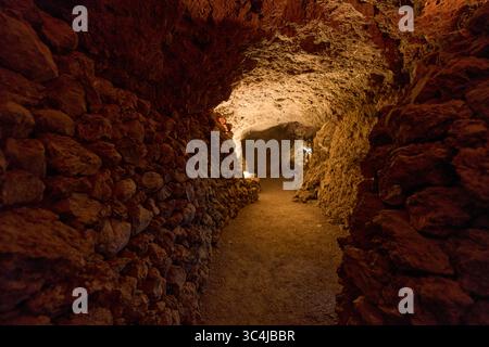 Intérieur d'une grotte volcanique formée par un ancien tube de lave avec des murs en pierre brute et un éclairage tamisé Banque D'Images