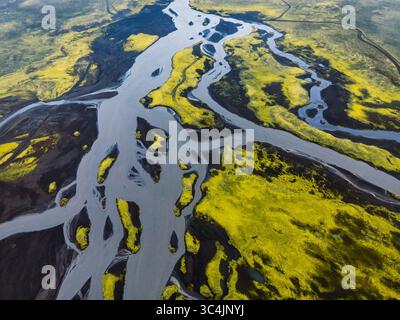 Vue aérienne des rivières glaciaires sculptant à travers des paysages moussseux verdoyants, créant des motifs complexes d'eau et de terre, Islande. Banque D'Images