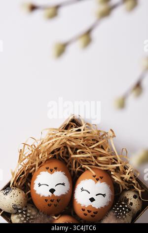 Oeuf de hibou peint à la main dans un nid avec des oeufs de caille. Espace pour votre texte. Banque D'Images